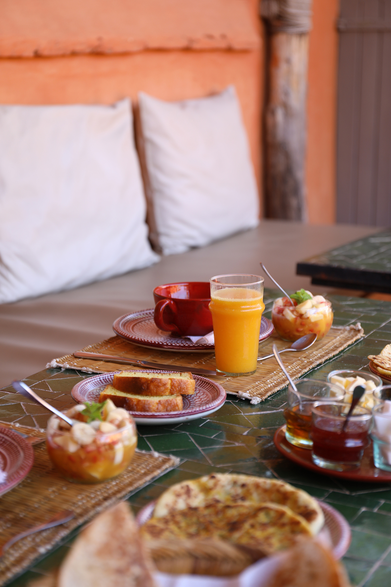 A breakfast of Moroccan breads, fruit and juice laid on a zellige table at Dar Akal
