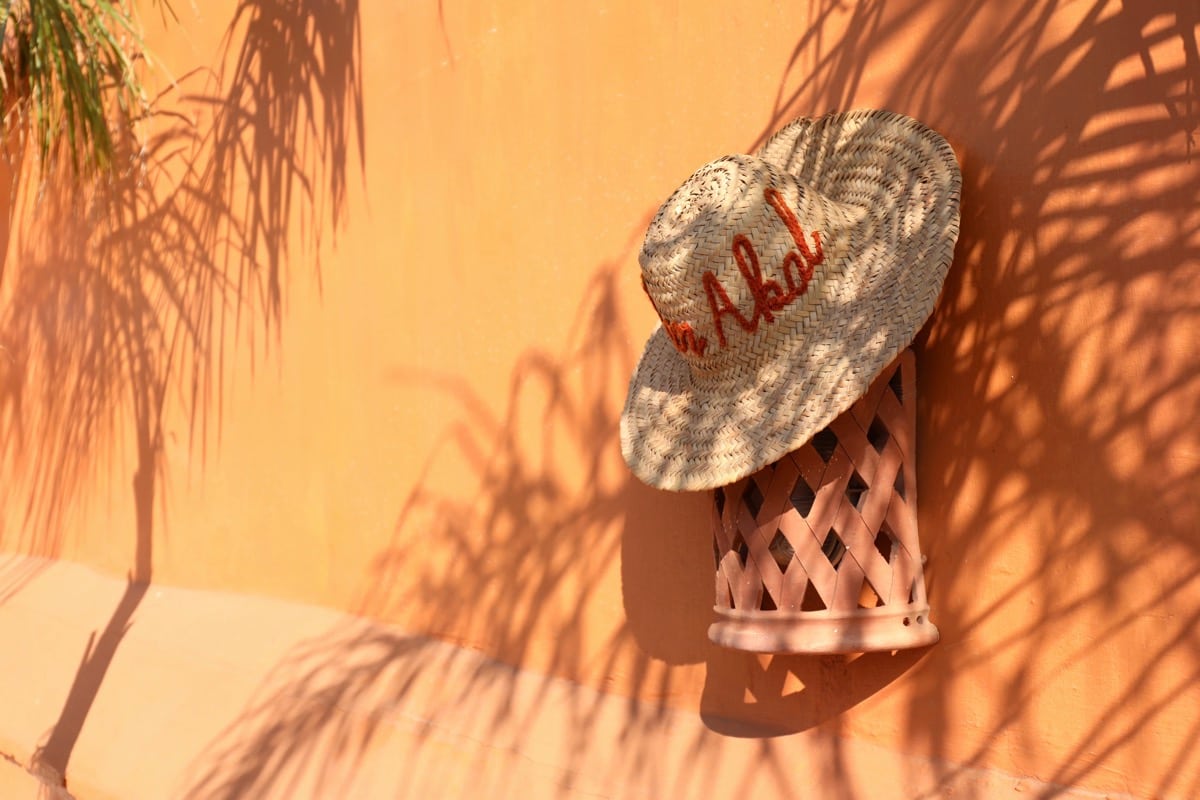 A woven Dar Akal hat surrounded by palm shadows on an ochre wall