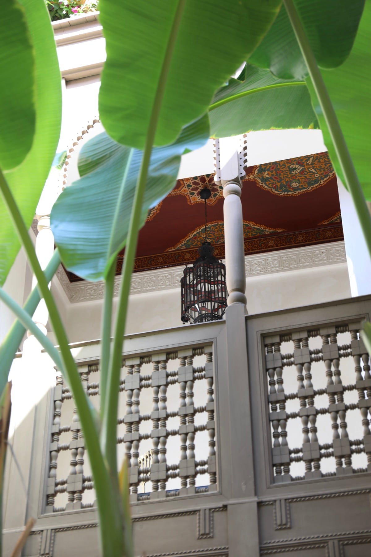 Banana leaves rising past carved screens and a hanging lantern