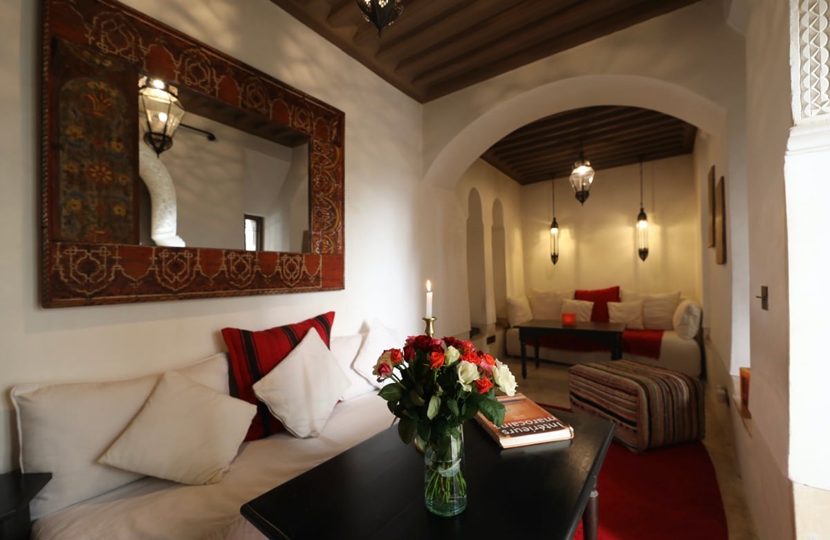 A long salon framed by arches, mirrors and red textiles