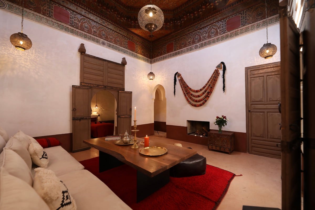The main salon beneath a painted ceiling, with a low table and fireplace