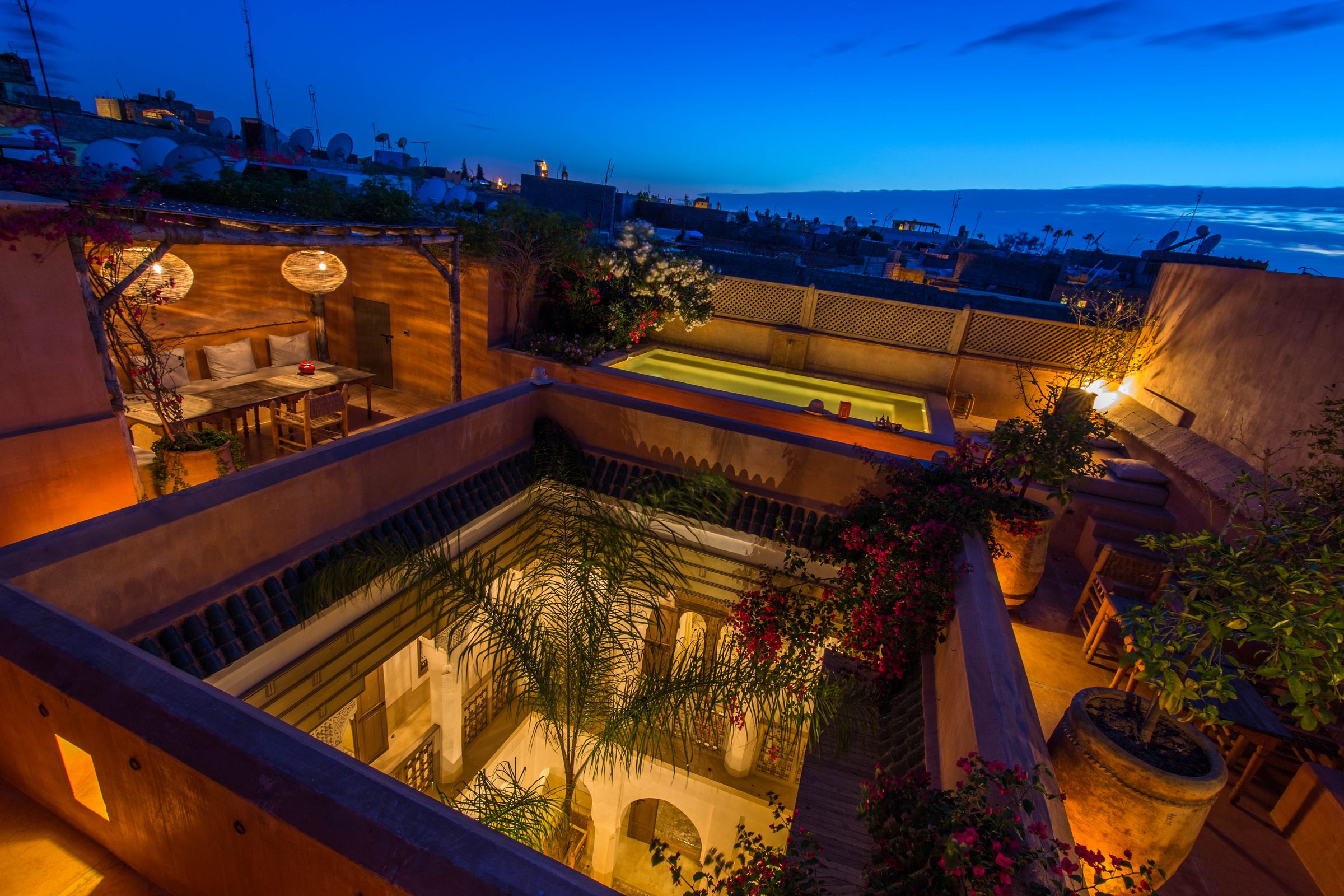 Dar Akal's courtyard and rooftop pool glowing above Marrakech at blue hour