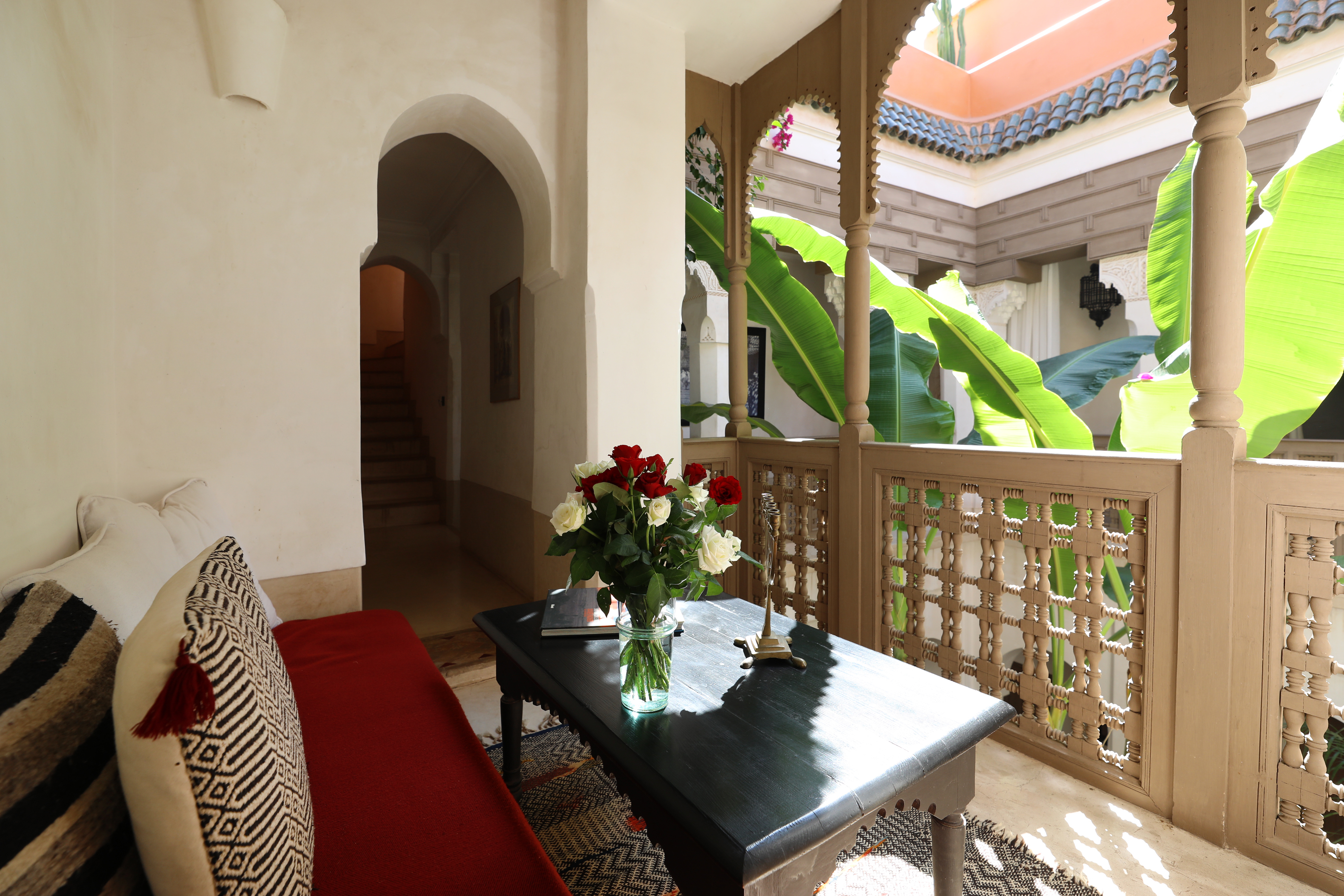 A sitting area on Dar Akal's carved upper gallery, open to the green courtyard