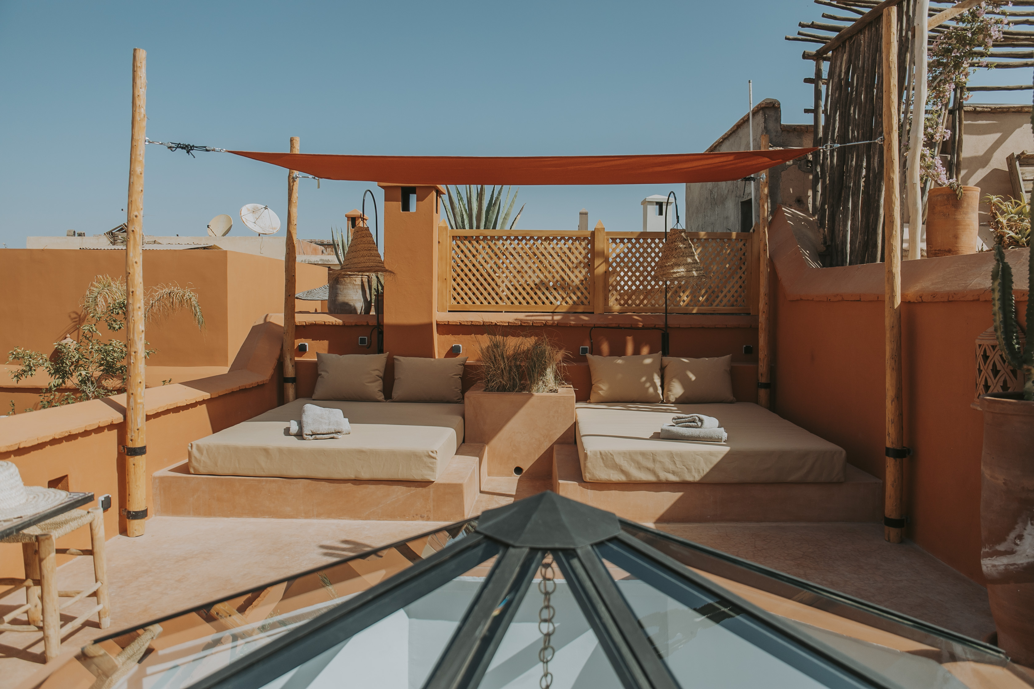 Two shaded daybeds on Dar Akal's terracotta rooftop terrace